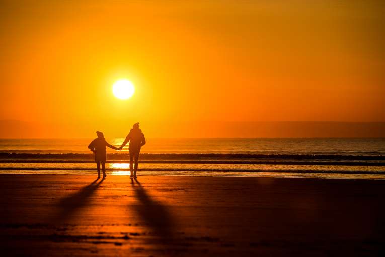 Couple walking on Saunton beach during a winter sunset
