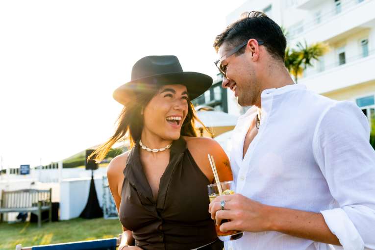 Two friends enjoying cocktails and smiling