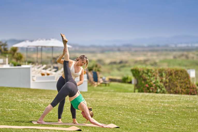 Teacher helping lady into a yoga pose 