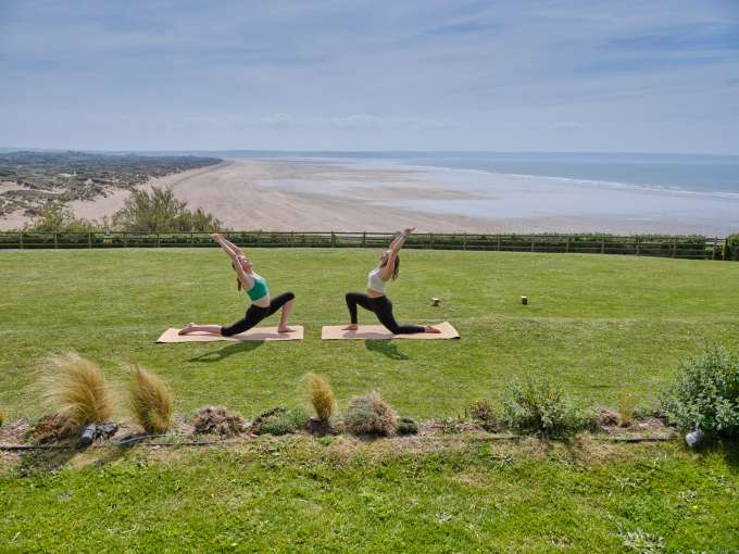 two ladies doing yoga outside on the lawn at Saunton Sands with a view of the beach