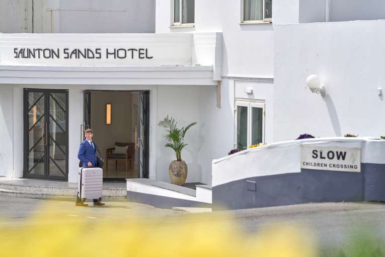 Man Holding a suitcase and brining it into the hotel
