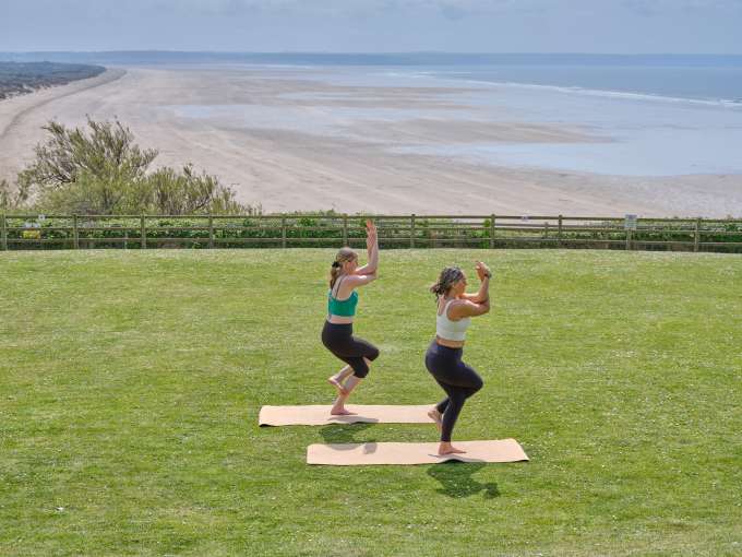 2 ladies outside the lawn at Saunton sands doing a yoga pose