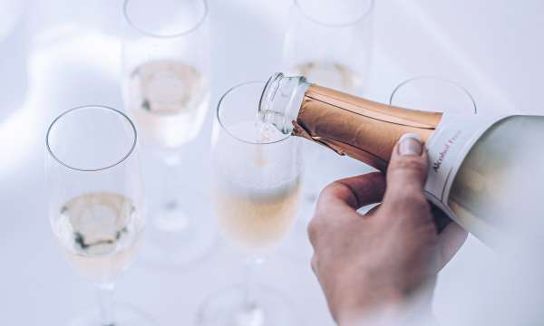 Waiter pouring Champagne into five glasses 
