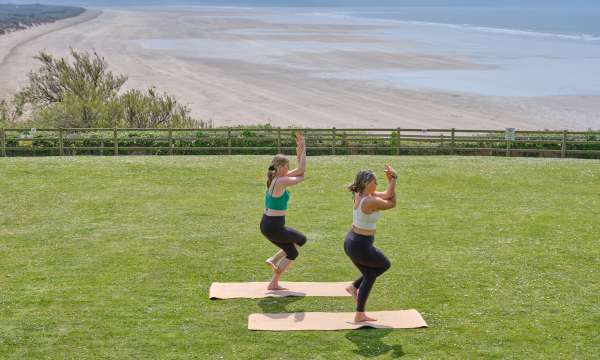 2 ladies outside the lawn at Saunton sands doing a yoga pose