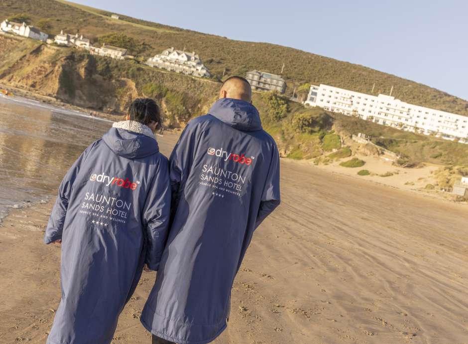 Couple walking on the beach wearing one of our branded Dryrobes