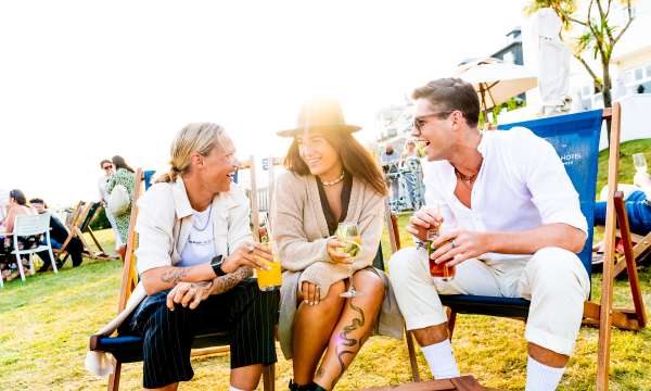 Three friends sat on the deck chairs with cocktails and smiling