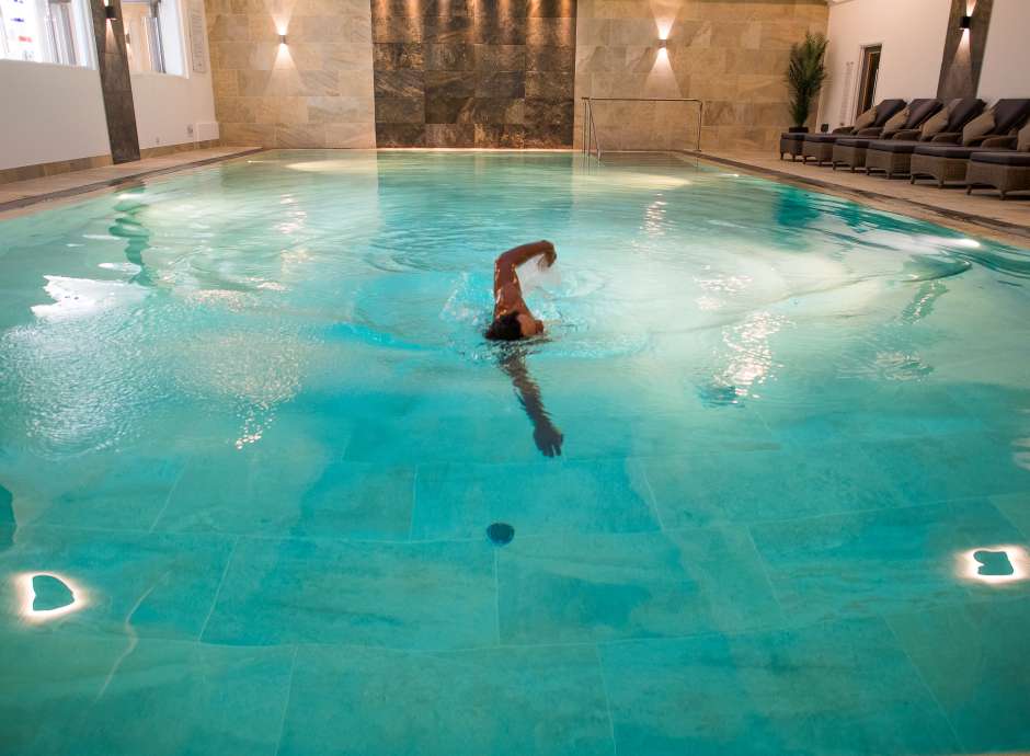 Man swimming in the indoor pool during the evening
